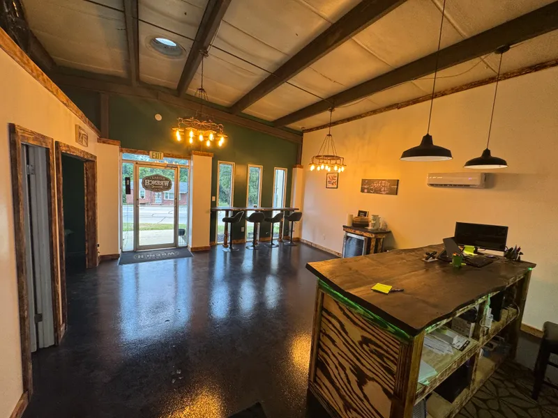 Window-bar seating with stools along the front windows, wagon-wheel chandelier above.
