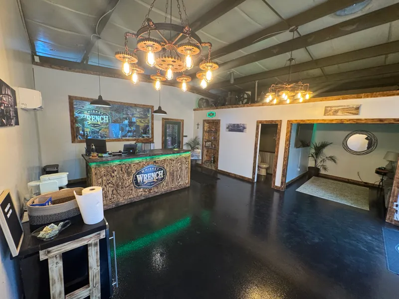 The lobby: burned-wood reception desk under wagon-wheel gear chandeliers with Edison bulbs.