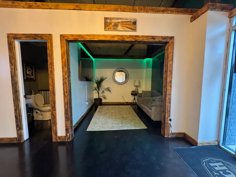 Lounge nook with couch, palm, mirror and green LED cove glow.