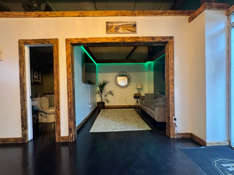 The customer lounge nook with a couch, rug and green LED cove lighting.