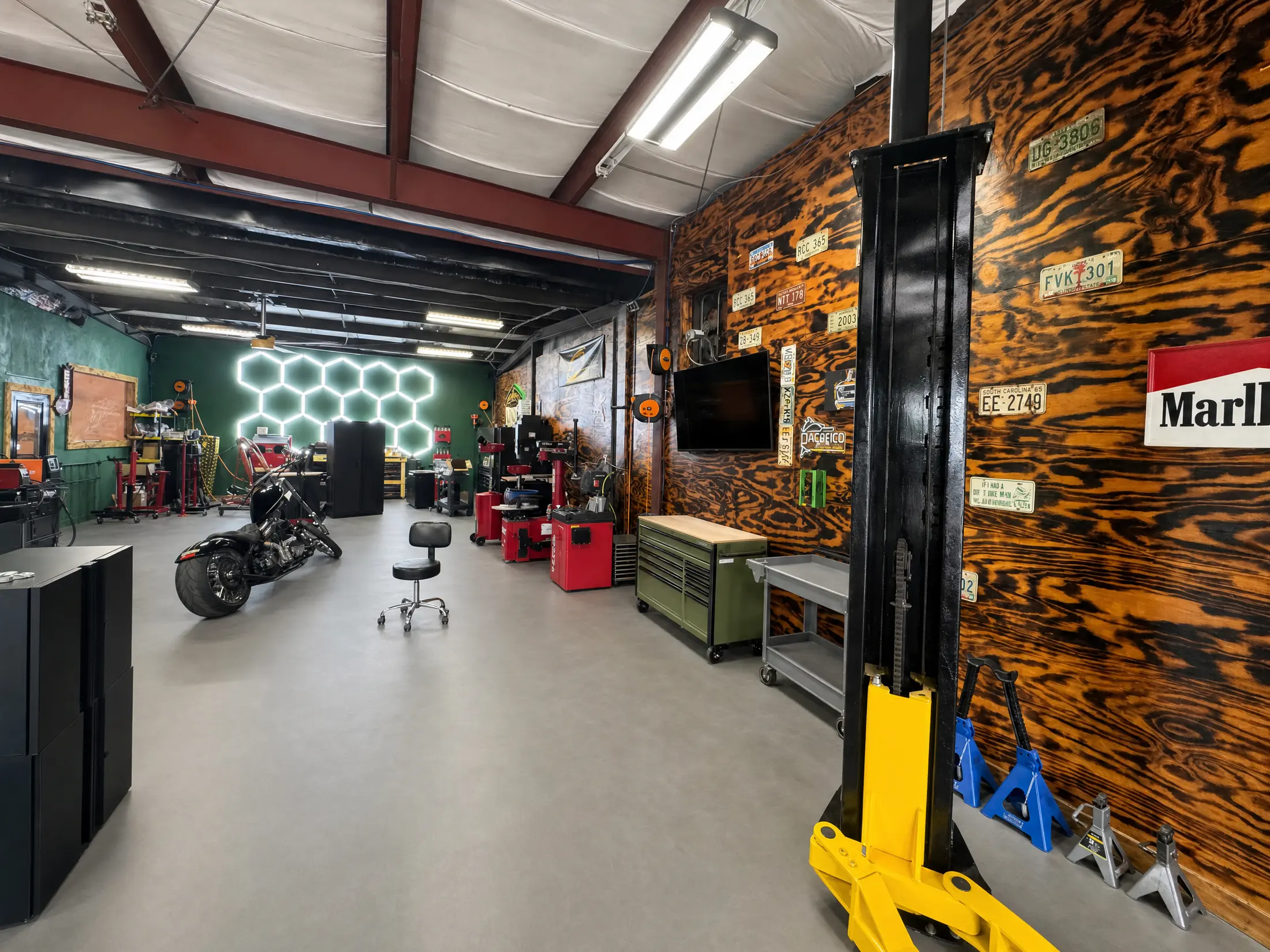 Whiskey Wrench shop floor: hex LED wall, tire machines, motorcycle on the floor, license-plate wall and single-post lift.