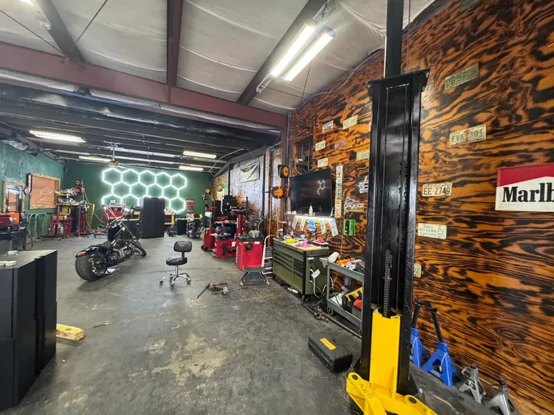 Shop floor with hex LED wall, tire machines and a motorcycle in for work.